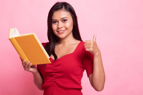 Joven mujer asiática pulgares arriba con un libro . — Foto de Stock