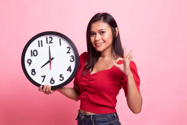 Jeune asiatique femme montrer OK avec une horloge . — Photo