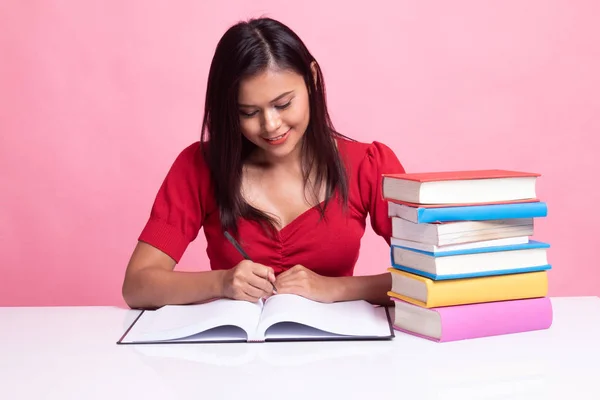 Joven mujer asiática leer un libro con libros en la mesa . — Foto de Stock