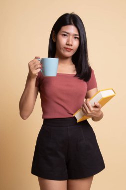 Bir kitap ve kahve ile genç Asyalı kadın.