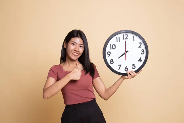 Young Asian woman thumbs up with a clock.