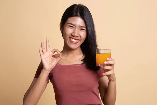 Jonge Aziatische vrouw drankje oranje sap Ok teken weergeven. — Stockfoto