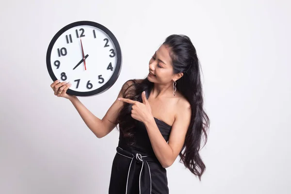 Young Asian woman point to a clock.