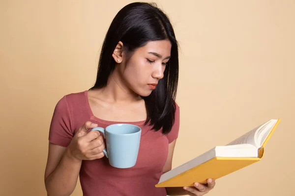 Junge asiatische Frau mit einem Buch und einer Tasse Kaffee. — Stockfoto