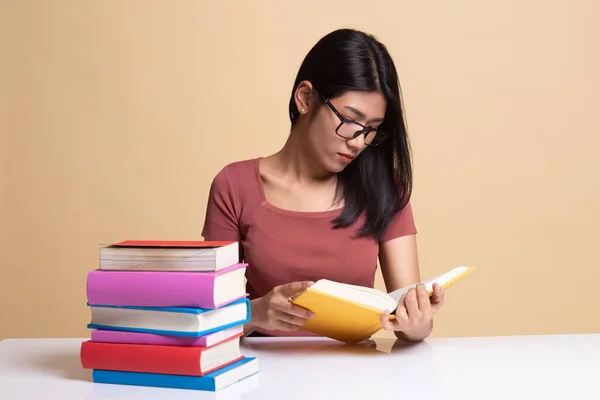 Junge Asiatin liest ein Buch mit Büchern auf dem Tisch. — Stockfoto