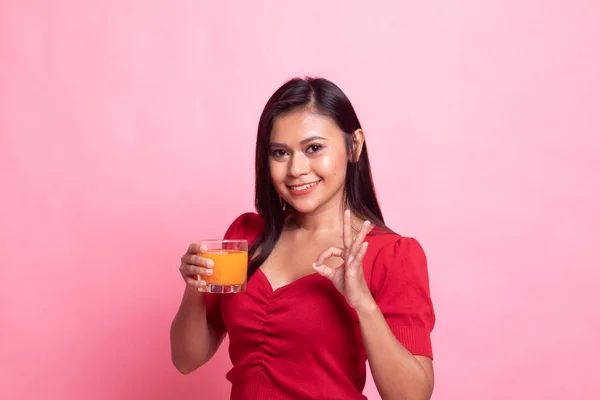 Jovem mulher asiática beber suco de laranja mostrar sinal OK . — Fotografia de Stock