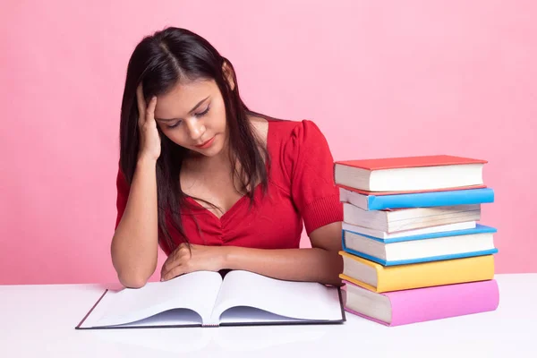 Exhausted Young Asian woman read a book with books on table. — Stock Photo, Image