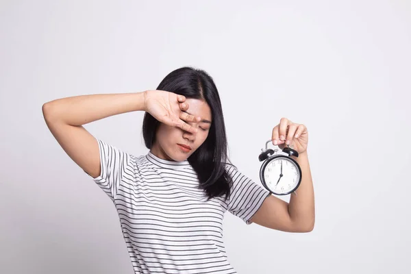 Sleepy young Asian woman with a clock in the morning.