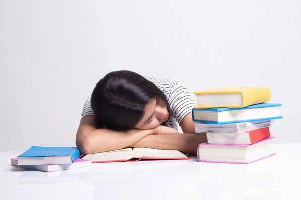 Utmattad ung asiatisk kvinna sömn med böcker på bord. — Stockfoto