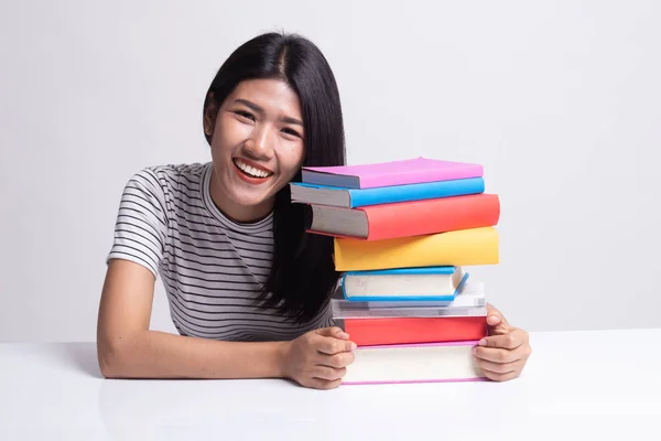 Glückliche junge Asiatin liest ein Buch mit Büchern auf dem Tisch. — Stockfoto