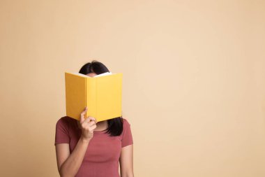 Bir kitapla genç Asyalı kadın kapak yüzü.