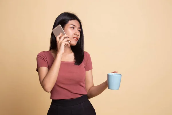 Young Asian woman with mobile phone and coffee cup.