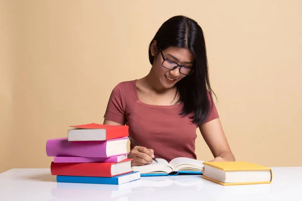 Junge Asiatin liest ein Buch mit Büchern auf dem Tisch. — Stockfoto