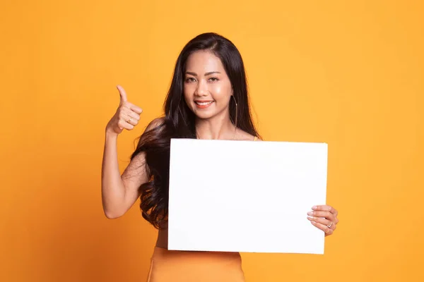 Молодая азиатка показывает большие пальцы с белым пустым знаком . — стоковое фото