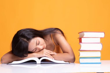 Genç Asyalı kadın uyku tablo kitapları ile yorgun.