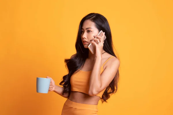 Jovem mulher asiática com telefone celular e xícara de café . — Fotografia de Stock