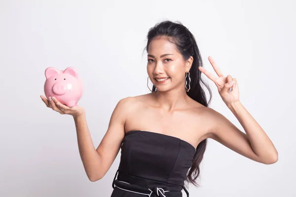 Mulher asiática mostrar sinal de vitória com banco de moeda de porco . — Fotografia de Stock