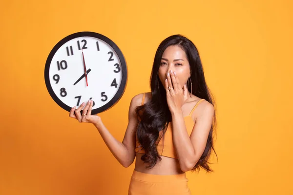 Sleepy joven asiática mujer con un reloj en la mañana . — Foto de Stock