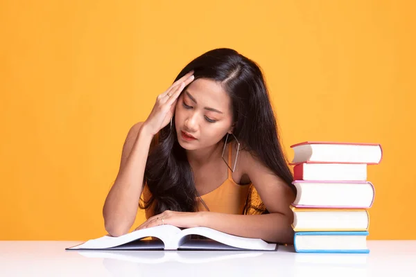 Vyčerpaná mladé asijské ženy četl knihu s knihami na stole. — Stock fotografie