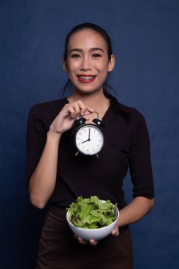 Saat ve salata ile genç Asyalı kadın.