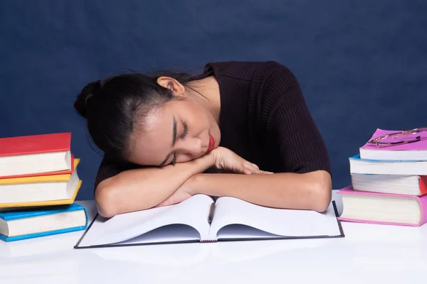 Uitgeput jonge Aziatische vrouw slapen met boeken op tafel. — Stockfoto