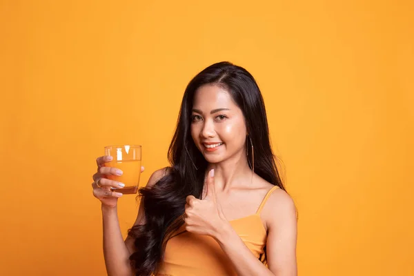 Jovem mulher asiática polegares até beber suco de laranja . — Fotografia de Stock