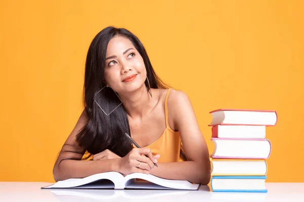 Ung asiatisk kvinna läsa en bok med böcker på bord. — Stockfoto