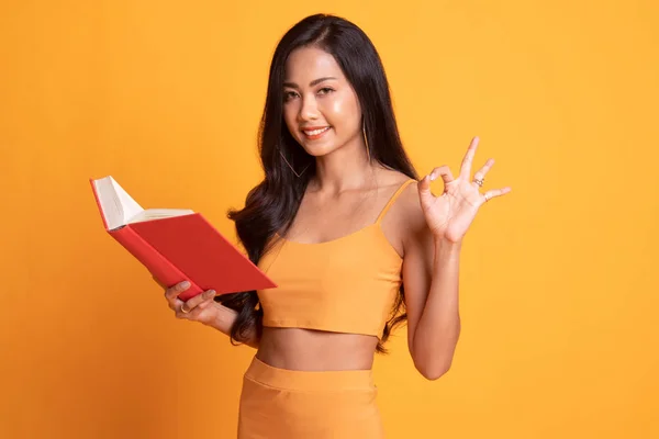 Jovem mulher asiática mostrar OK com um livro . — Fotografia de Stock