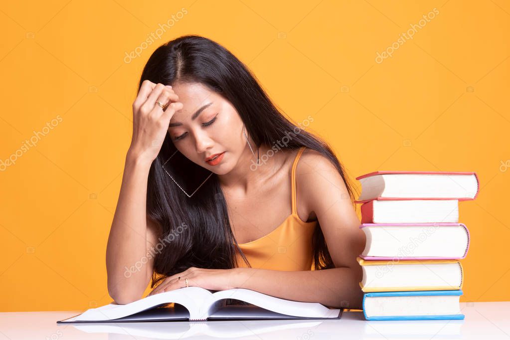 Exhausted Asian woman got headache read a book with books on tab