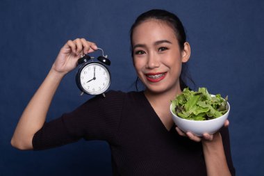 Saat ve salata ile genç Asyalı kadın.