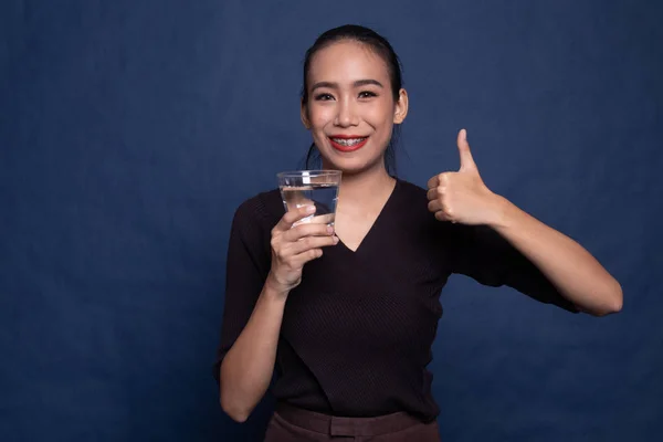 若いアジア女性の飲用水のガラスと親指. — ストック写真