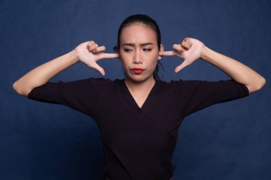 Genç Asyalı kadın parmakları ile her iki kulak engellemek.