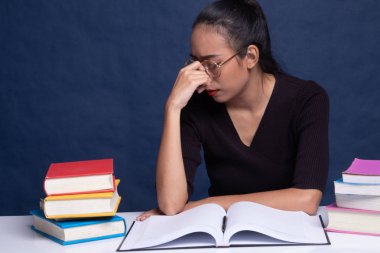 Yorgun Asyalı kadın baş ağrısı okuma sekmesinde kitaplarla bir kitap aldım.