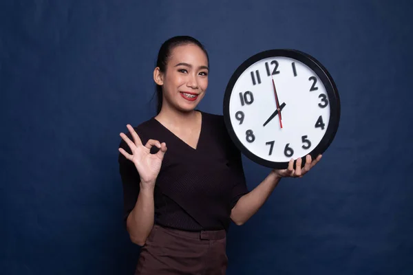 Jeune asiatique femme montrer OK avec une horloge . — Photo