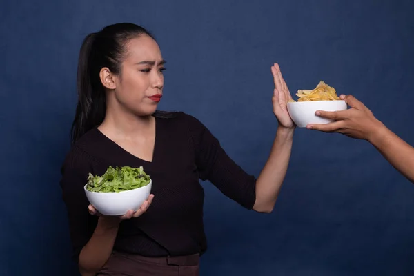 Jonge Aziatische vrouw met salade nee zeggen tegen potato chips. — Stockfoto