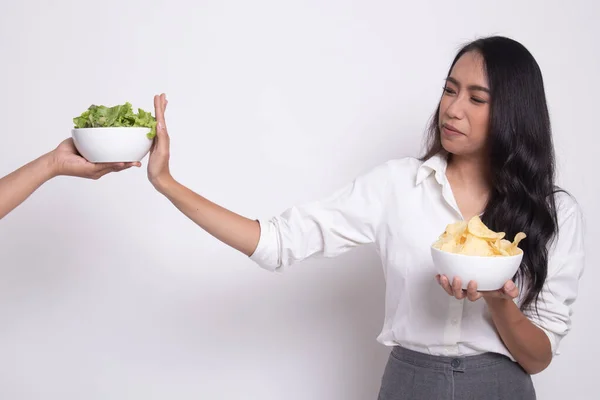 ポテトチップスを持つ若いアジア女性はサラダにノーと言う. — ストック写真