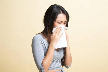 Genç Asyalı kadın hastalandı ve bej arka planda grip oldu.