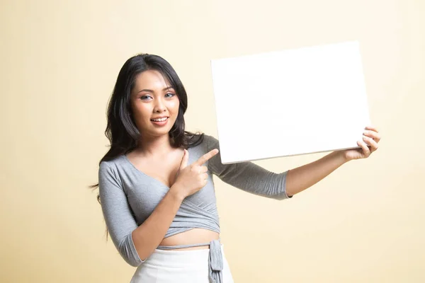 年轻的亚洲女人指着米色背景的空白签名 — 图库照片