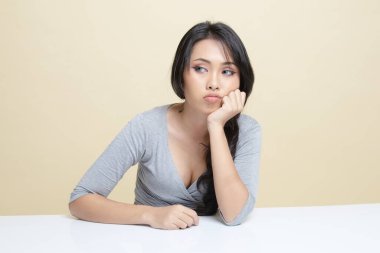 Asyalı kız bej arka planda sıkılıyor.