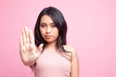 Pembe arka planda dur işareti yapan Asyalı bir kadının portresi