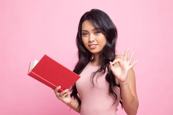 Junge Asiatin Zeigt Mit Einem Buch Auf Rosa Hintergrund — Stockfoto