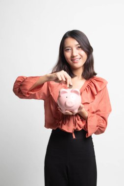 Beyaz arka plan üzerinde sikke ve domuz para banka ile Asyalı kadın