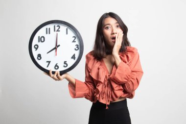 Beyaz arka plan üzerinde sabah bir saat ile uykulu genç Asyalı kadın