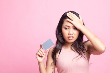 Genç Asyalı kadın baş ağrısı ve pembe arka planda boş bir kart.