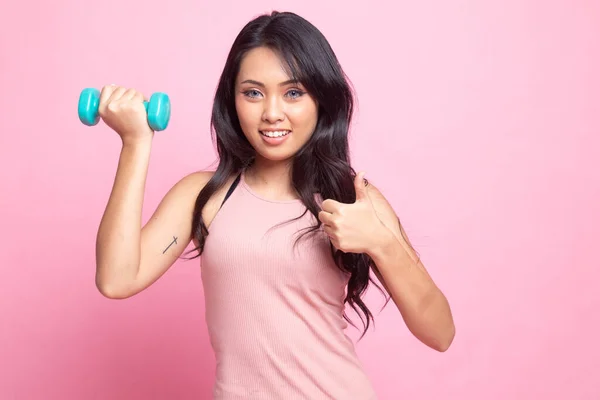 健康的亚洲女人的大拇指上挂着粉色背景的哑铃 — 图库照片