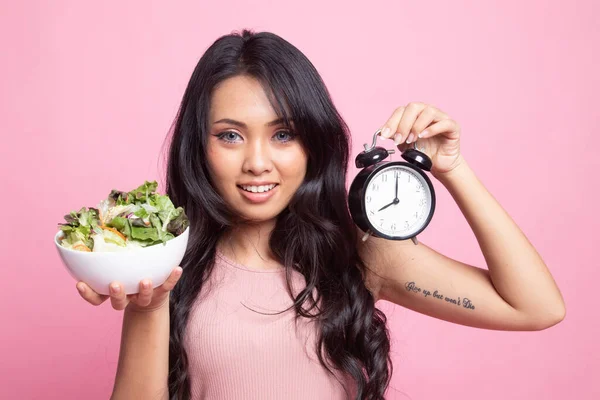 年轻的亚洲女人 背景是粉色的钟表和沙拉 — 图库照片