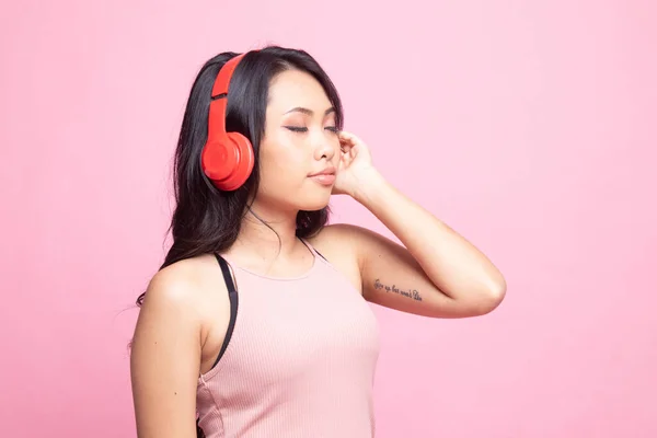 漂亮的亚洲女孩 带着粉色背景的耳机在听音乐 — 图库照片