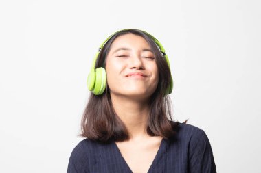 Güzel Asyalı kız beyaz arka planda kulaklıklarıyla müzik dinliyor.