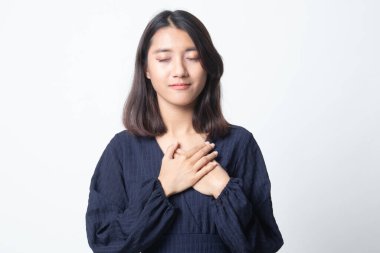 Sadık kadın gözlerini kapar ve ellerini kalbine yakın tutar. Beyaz arka planda nezaketini gösterir.