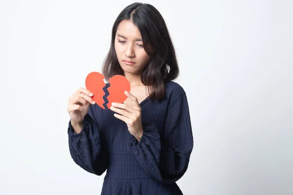 Beautiful young Asian woman with broken heart on white background